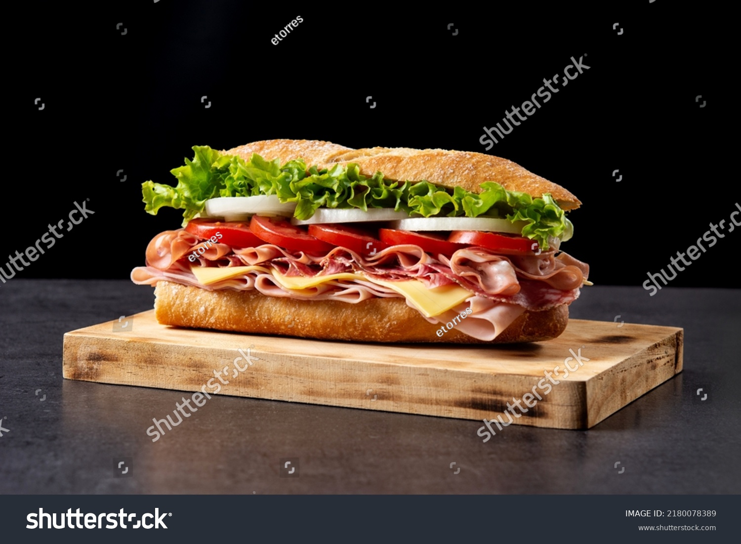 Submarine sandwich with ham, cheese, lettuce, tomatoes,onion, mortadella and sausage on wooden table #2180078389