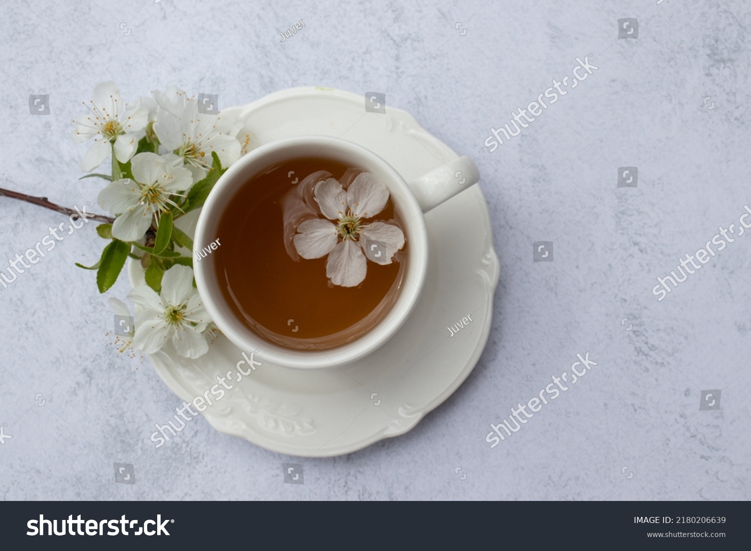 Cup of tea with white flowers on marble table. Minimalist still life in white color. Relaxation, healthy lifestyle, self care concept. Flat lay, top view #2180206639