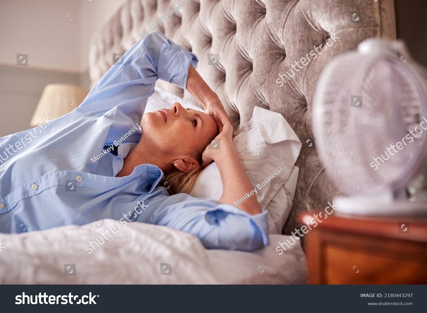 Menopausal Mature Woman Suffering With Insomnia In Bed At Home Using Electric Fan #2180443297