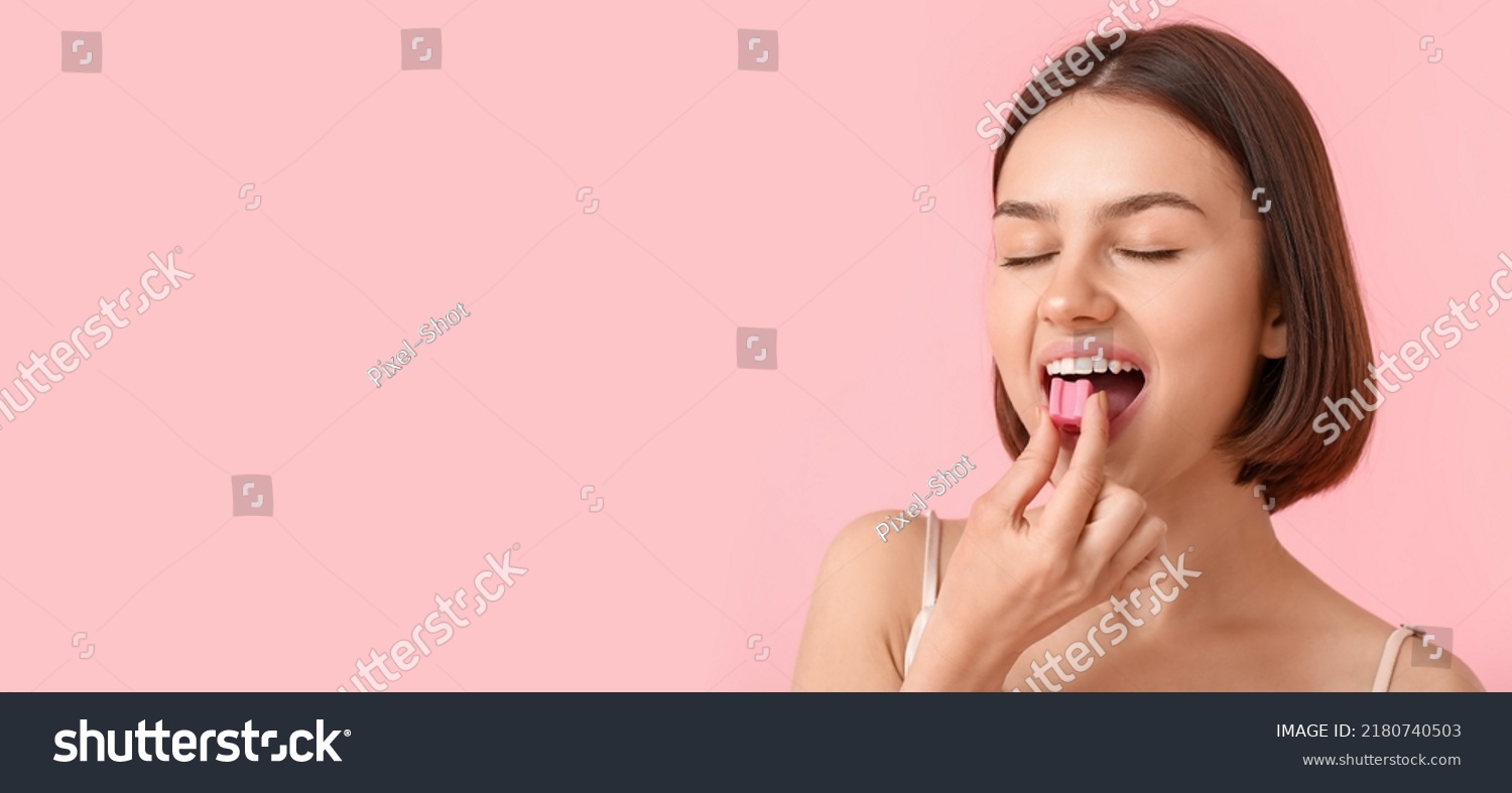 Young woman with chewing gum on pink background with space for text #2180740503