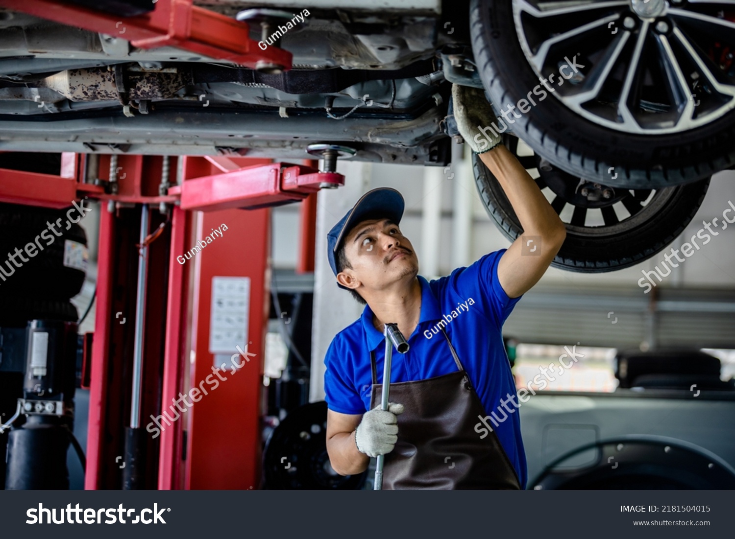 Auto mechanic repairman using a socket wrench working auto suspension repair in the garage, change spare part, check the mileage of the car, checking and maintenance service concept. #2181504015