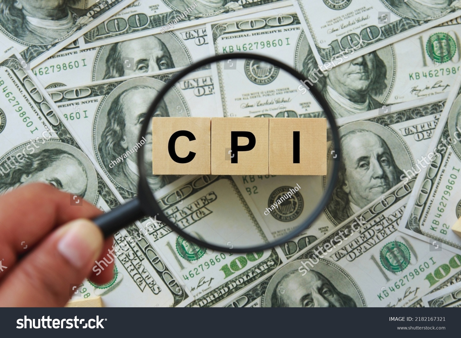 CPI, consumer price index symbol. hand holding magnifying glass investigating wooden block with words CPI, consumer price index on dollar bills. Business and CPI, consumer price index concept. #2182167321