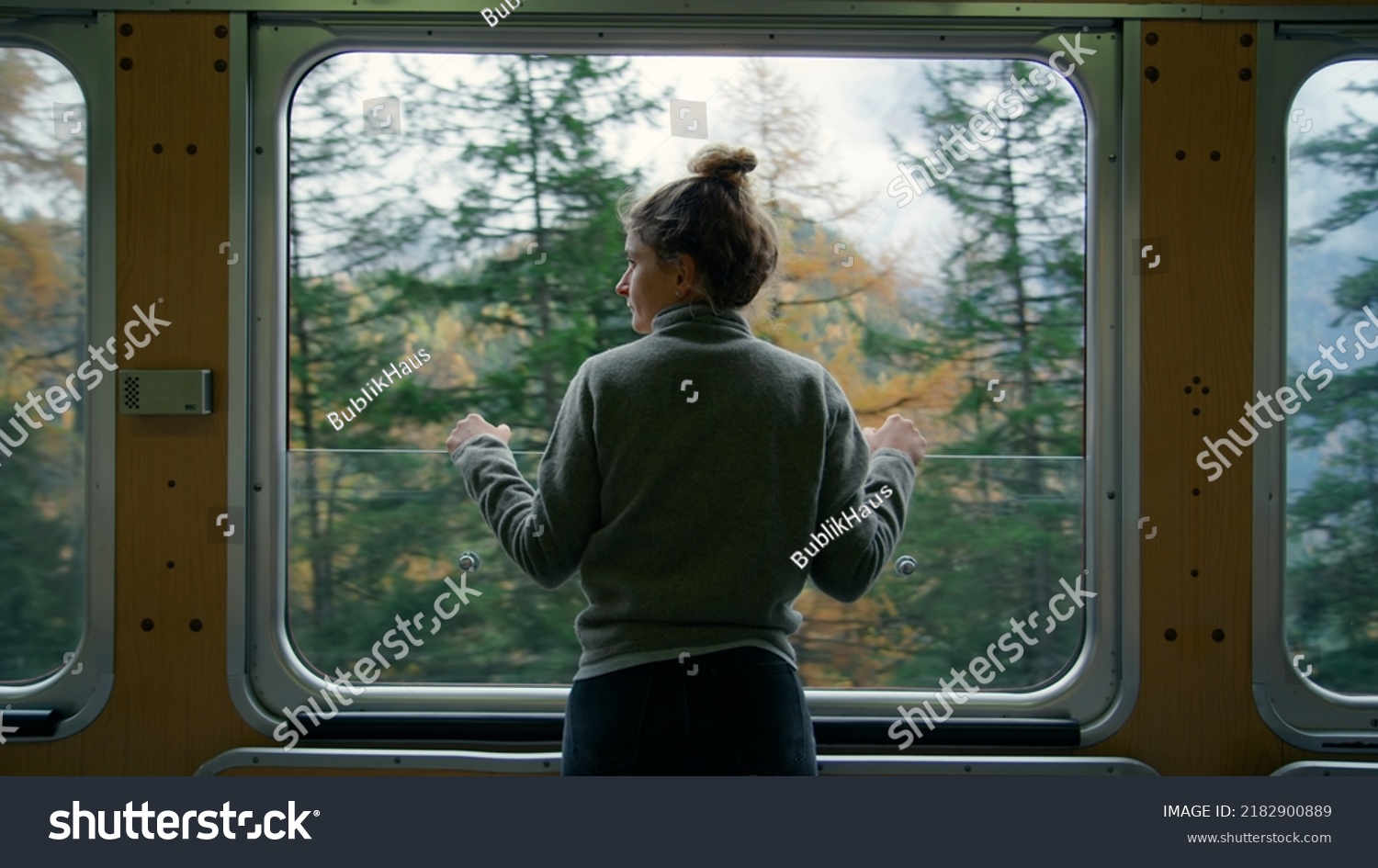 Cinematic and symmetrical beautiful shot of female traveler, travel blogger and inspired adventurer hang out of train window, look at amazing landscape of autumn mountains #2182900889