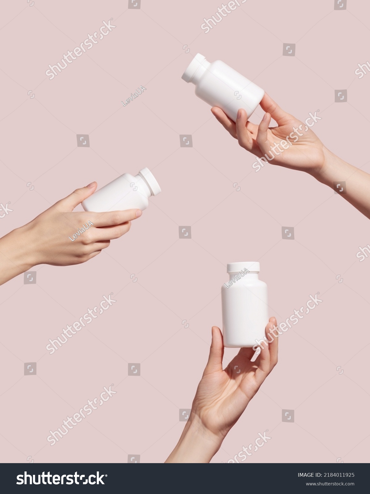 Hands holding blank white plastic tubes on pink background. Packaging for pills or capsules. Medic product branding mockup. High quality photo  #2184011925