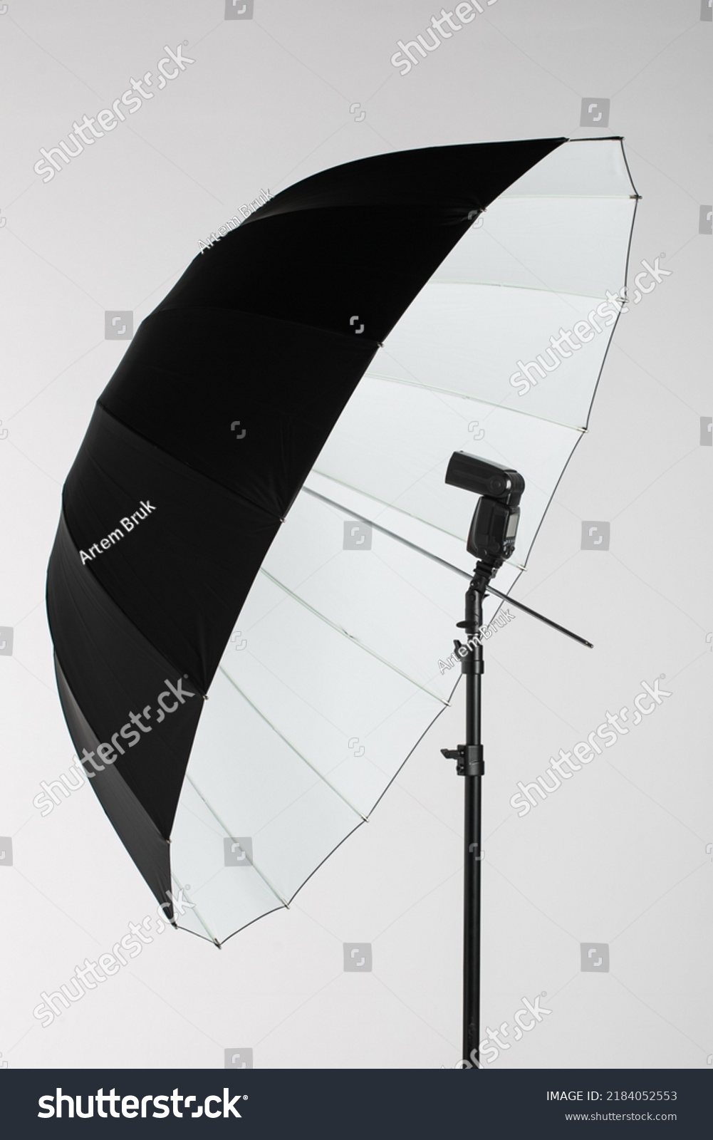 Camera flash head mounted on stand with umbrella light reflector in photography studio #2184052553