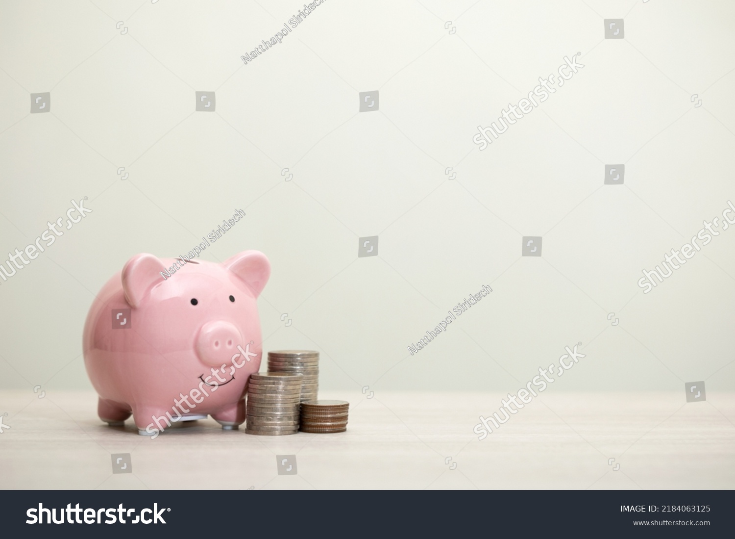 pink piggy bank smiling and coins on the table, for saving money wealth, and financial concepts, copy space #2184063125