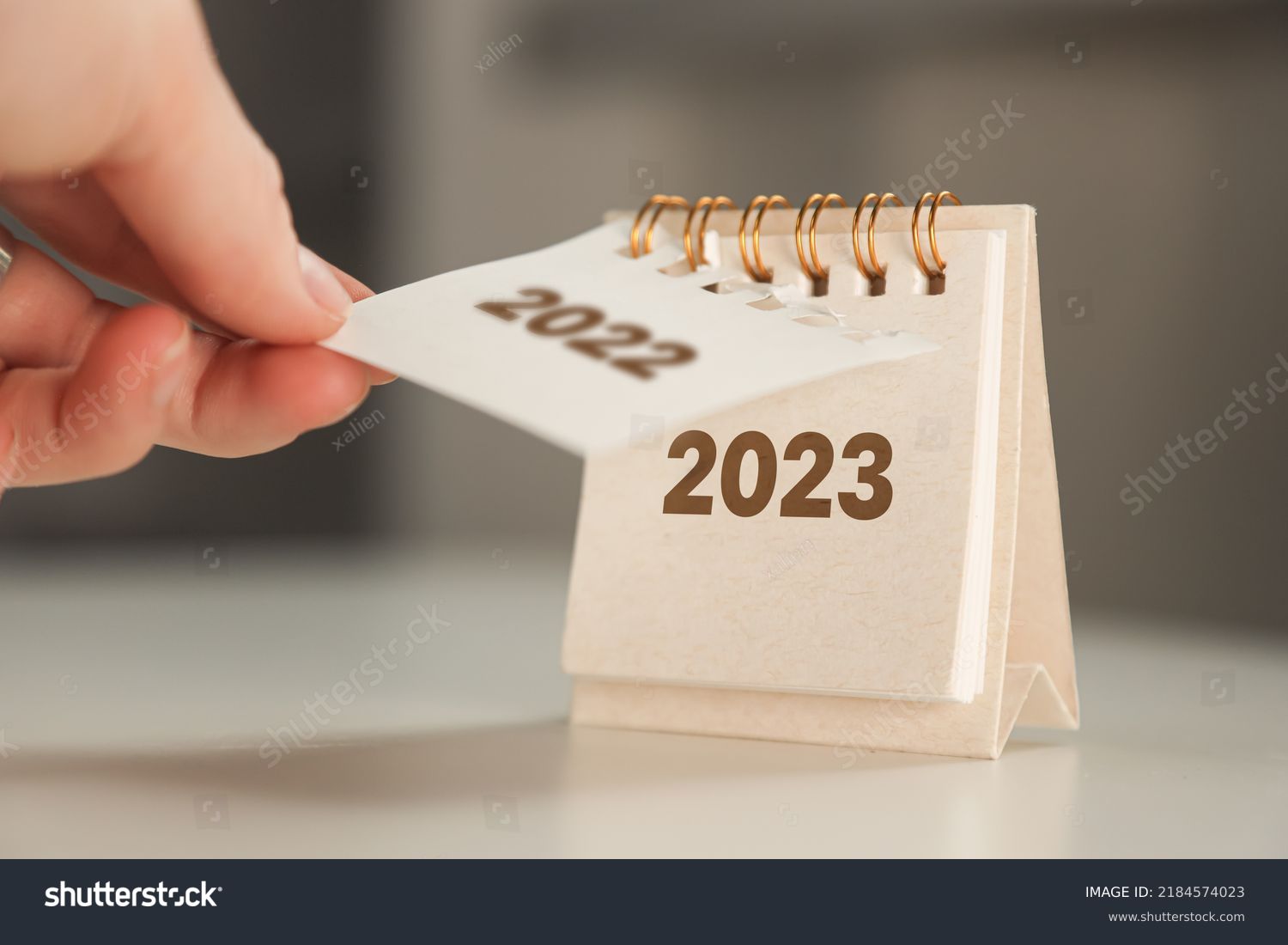 a woman's hand turns over a calendar sheet. year change from 2022 to 2023. #2184574023