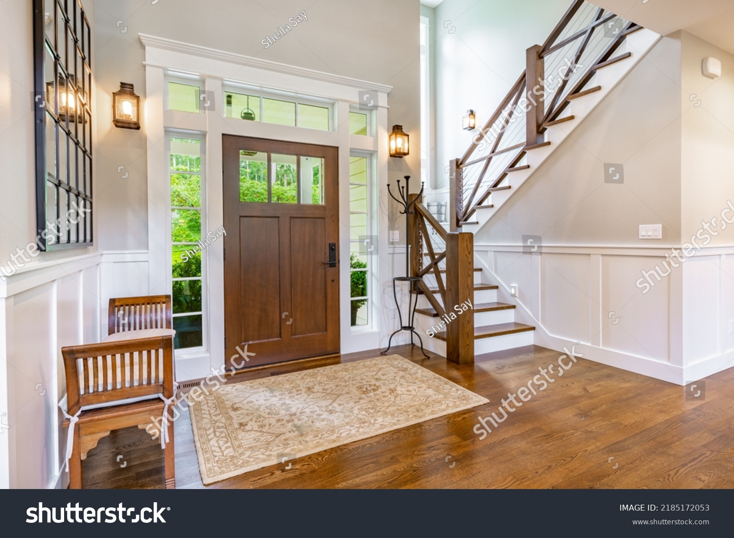 front entry foyer of a luxurious home rich wood tones staircase bench with a welcoming feel #2185172053