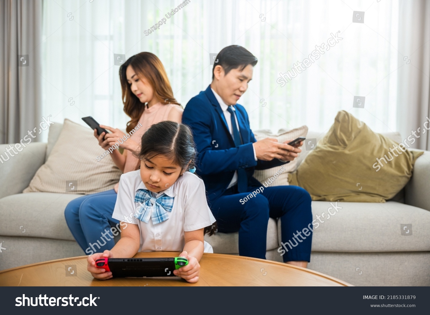 Family don't care about each other. Asian parents ignore their child and looking at their mobile phone at home, gadgets dependence overuse internet social media addiction on sofa living room #2185331879