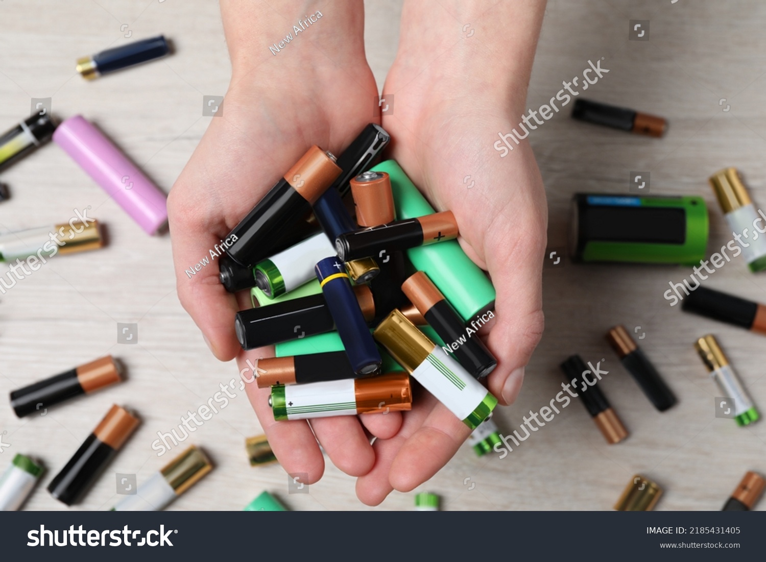 Woman holding many used electric batteries in her hands over white table, closeup #2185431405