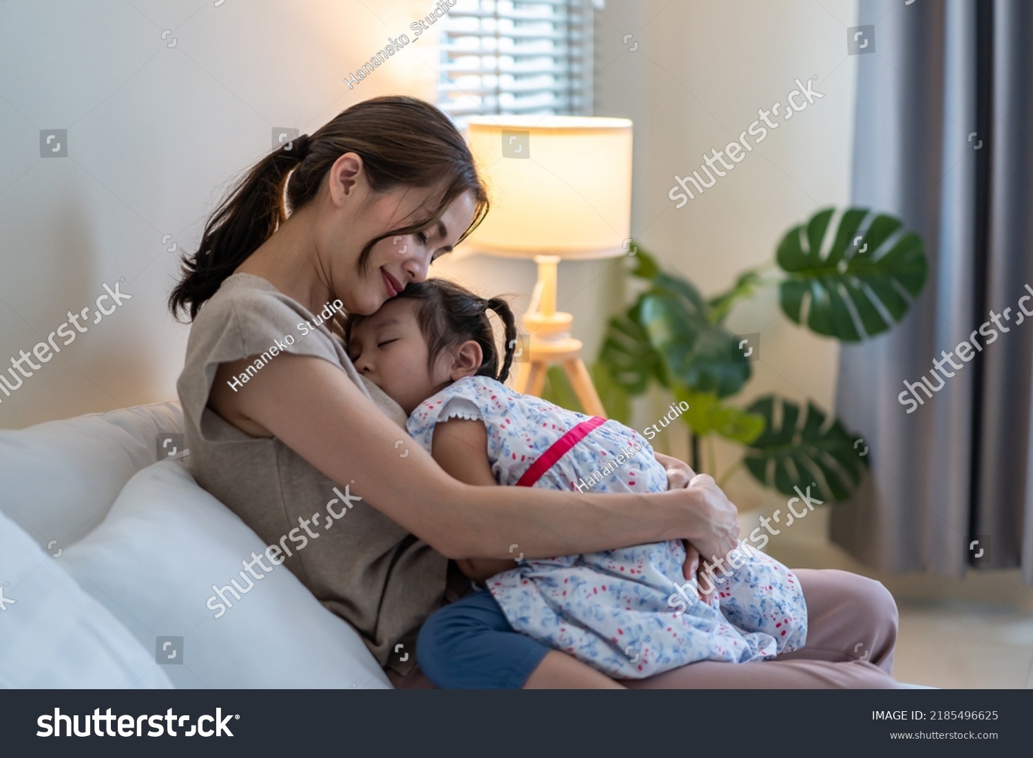 Asian beautiful mother hug sleeping baby girl in her arms with gently. Loving young parent holding small baby to rest on shoulder and sleep with young daughter. Parenting relationship at home concept. #2185496625