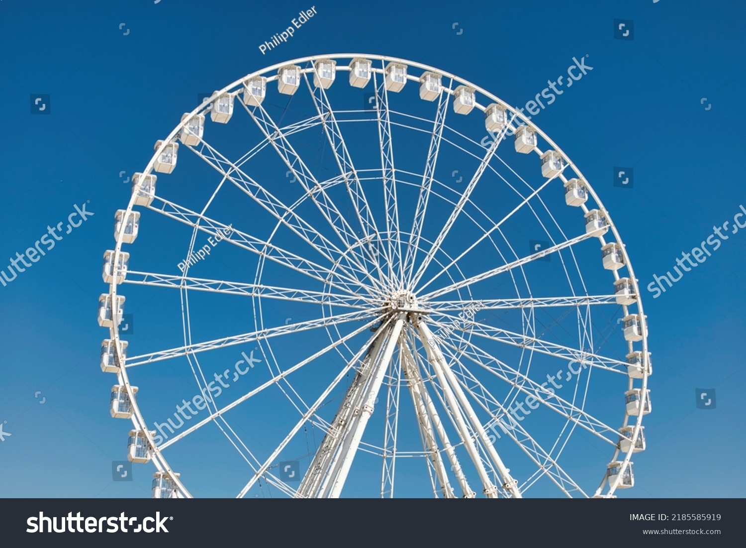 Big, tall white Ferris wheel in front of a perfect blue sky at the oceanfront in Marseille, France. Happy summer vacation feelings.  #2185585919