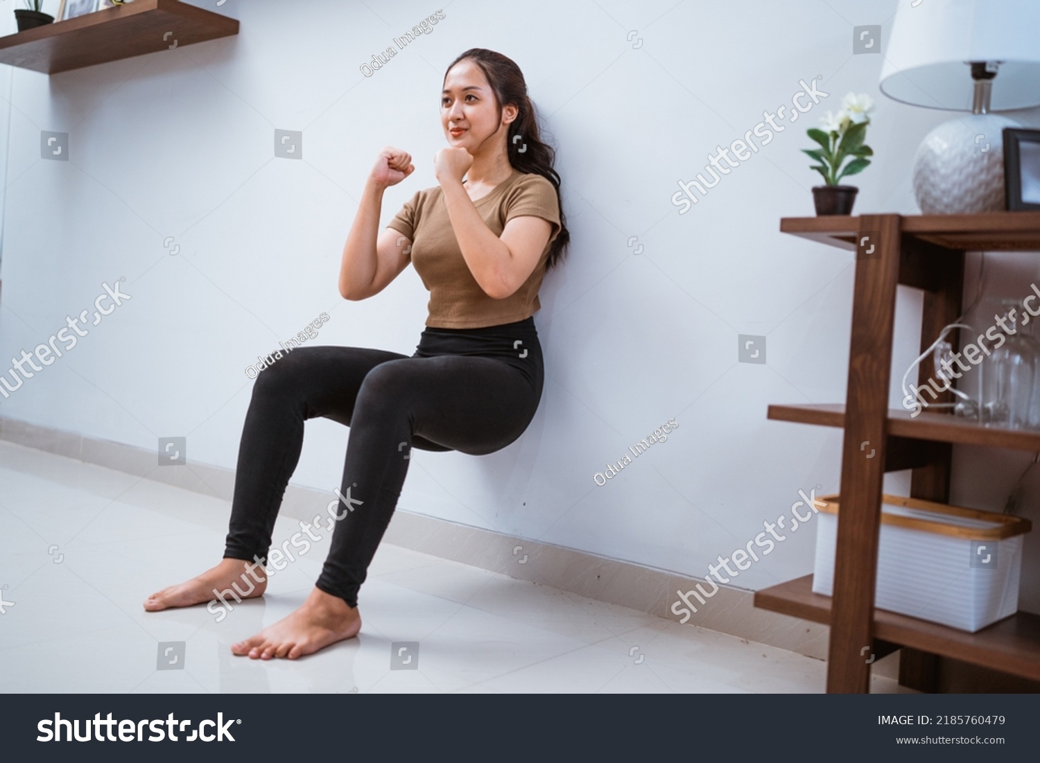 portrait of young asian woman squating against the wall at home #2185760479