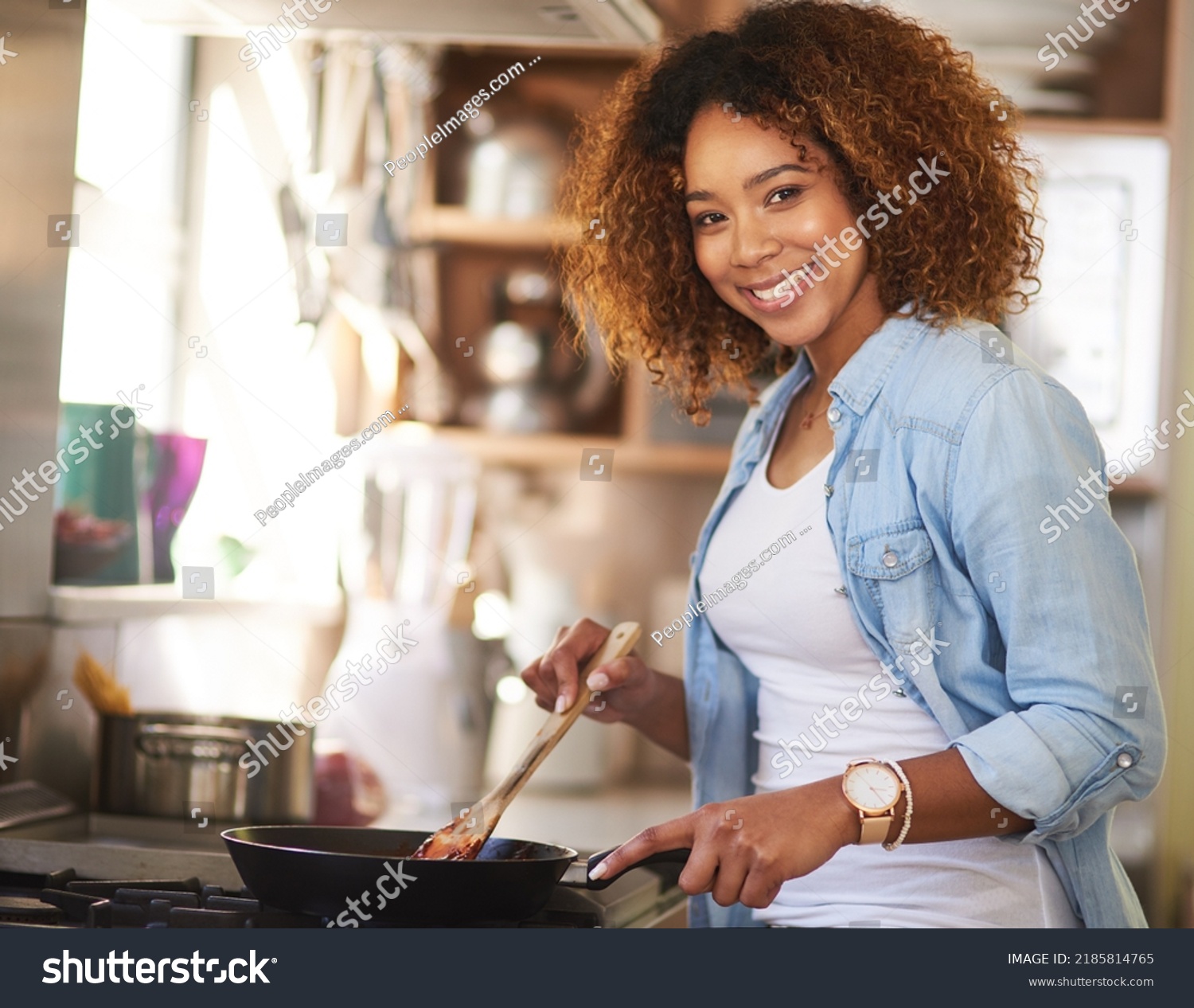 Whipping up something delicious just for you. Portrait of a happy young woman preparing a meal on the stove at home. #2185814765