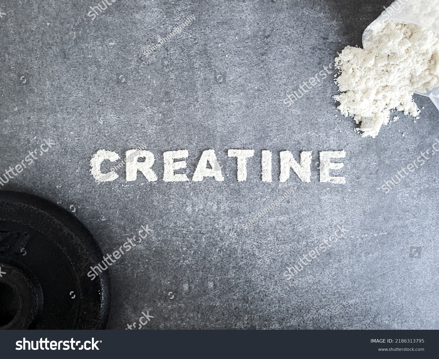 Creatine powder text font for Creatin popular sports supplement used to icrese muscle mass on stone background with scoop of creatine powder and sumbbell concept #2186313795