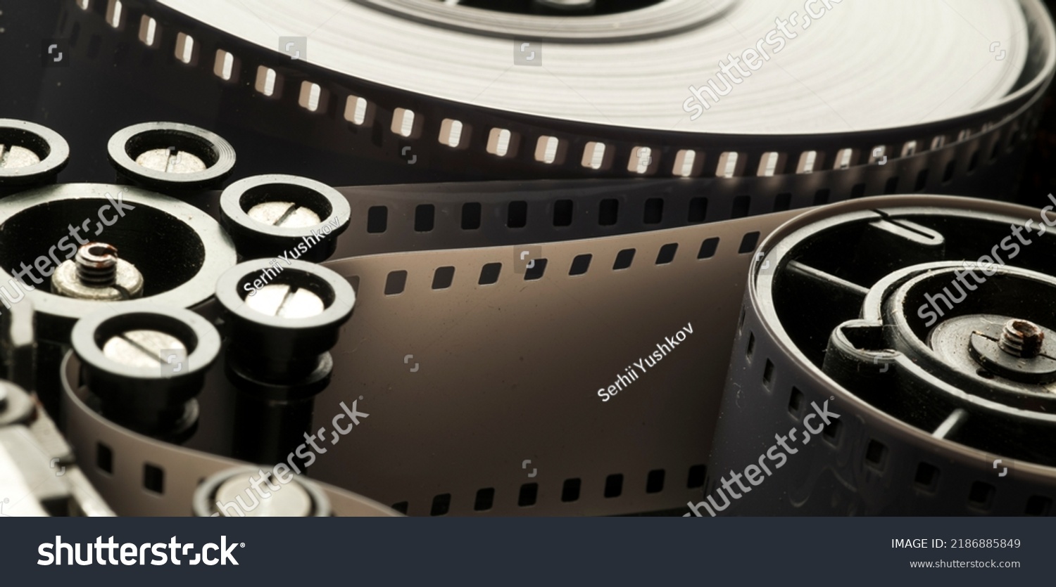 a roll of film in a film camera cassette. negative film in the tape drive mechanism of the cassette. show business film production technology concept #2186885849