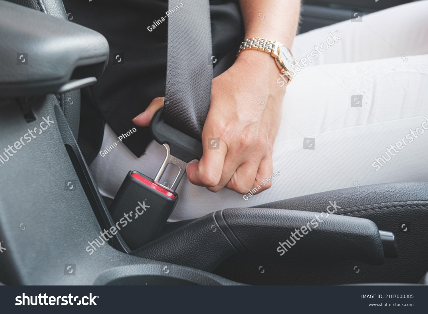 Close-up of a woman's hand fastening a seat belt in a car. Woman driver fastens her seat belt before driving. Driving safety concept. #2187000385