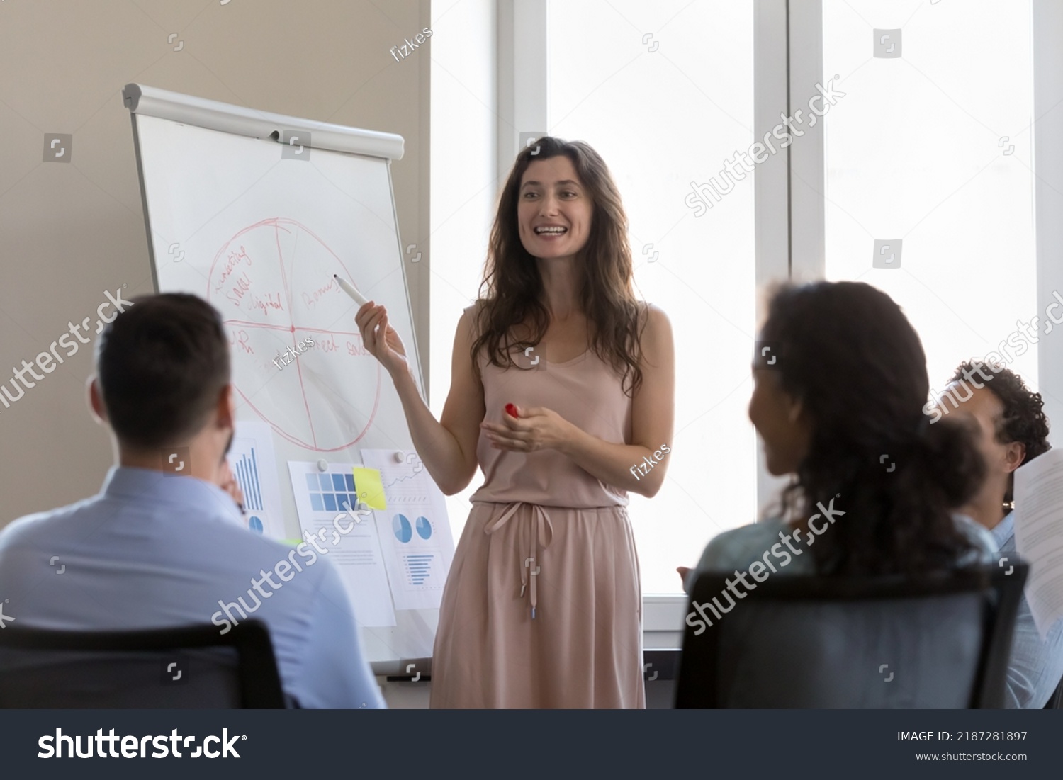 Business training event, presentation for staff or clients concept. Multi ethnic seminar participants listen to attractive confident smiling trainer make speech, give information shown on flip chart #2187281897