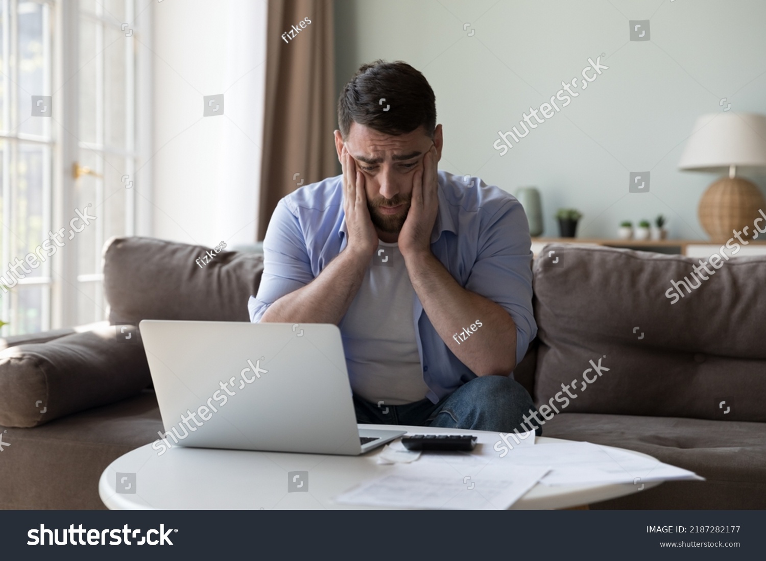 Millennial man counted income and expenses looks upset because of lack of funds for monthly mortgage payments feels desperate sit near heap of bills feels stressed. Financial failure, debts concept #2187282177