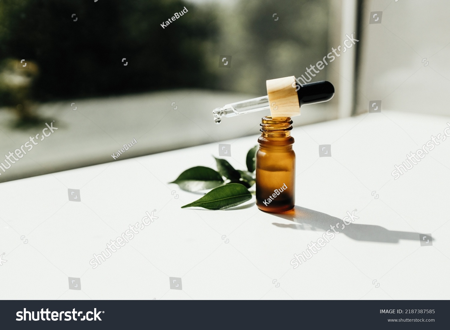 Amber bottle with serum or essential oil. Natural organic cosmetic, aromatherapy message oil. A drop of oil at the end of a pipette #2187387585