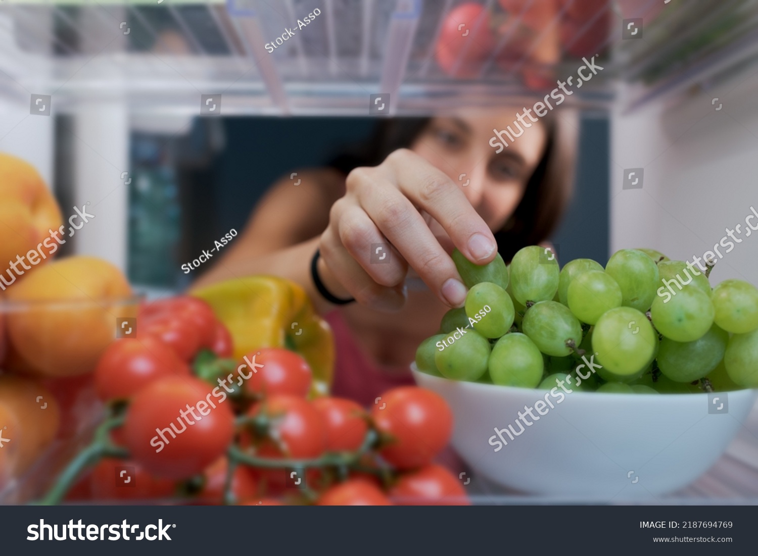 Young woman having a healthy snack, she is taking fruit in the fridge, POV shot from inside of the fridge #2187694769