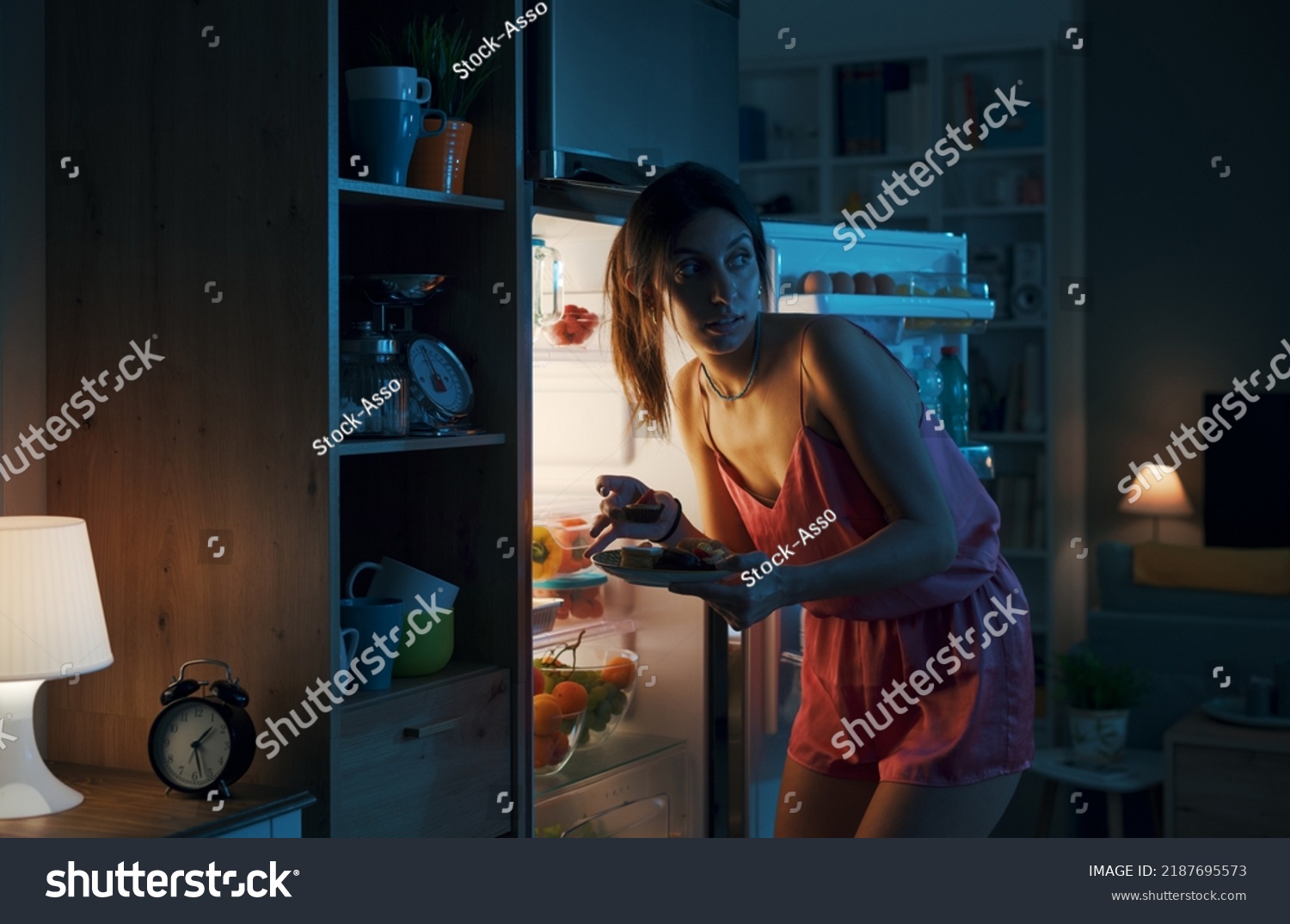 Hungry woman looking in the fridge and eating delicious pastries at night, she is breaking her diet #2187695573