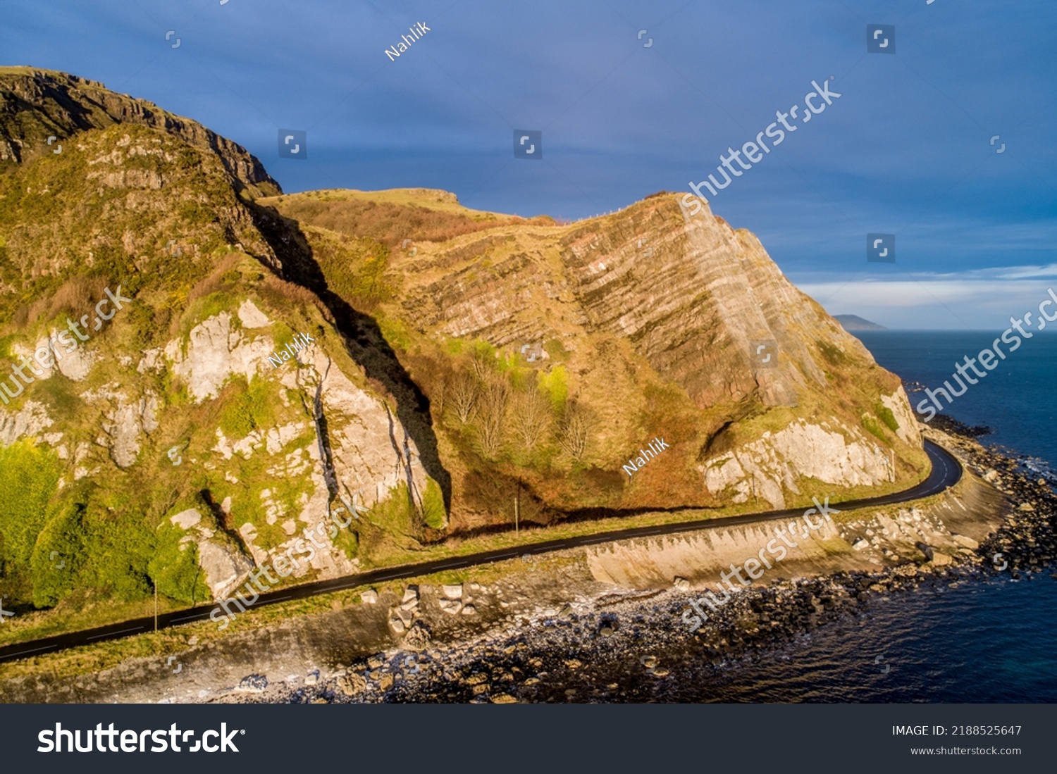 Northern Ireland, UK. Atlantic coast. Cliffs and Antrim Coast Road, a.k.a. Causeway Costal Route. One of the most scenic coastal roads in Europe. Aerial view near Garron Point in sunrise light #2188525647