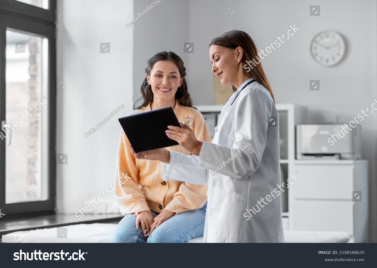 medicine, healthcare and people concept - female doctor with tablet pc computer talking to smiling woman patient at hospital #2188588635