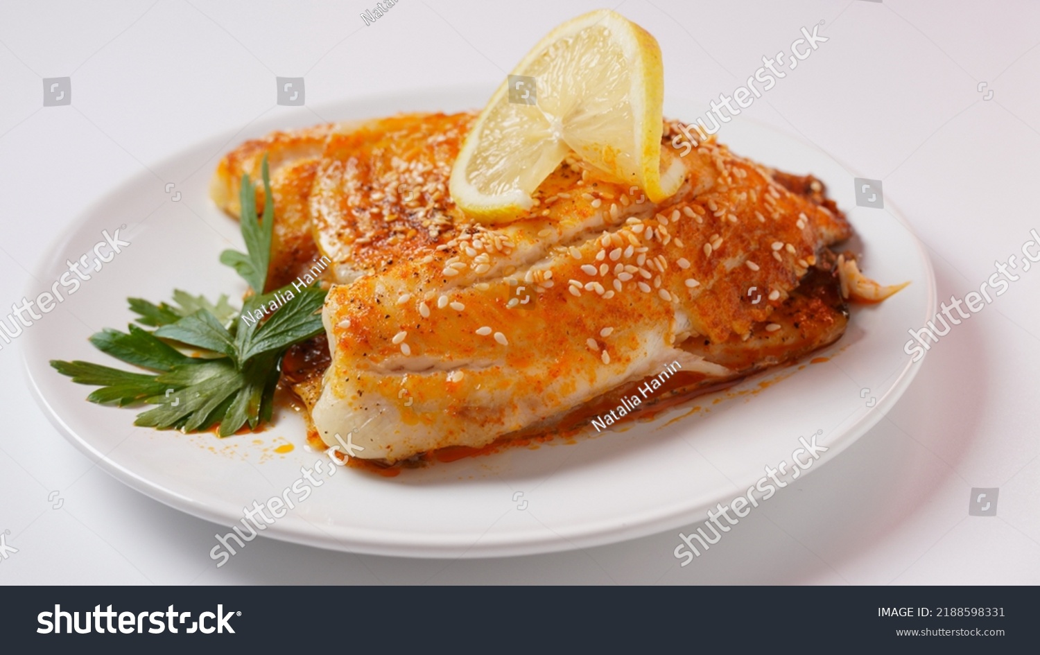Fresh backed tilapia fillet on white plate with lemon and herbs #2188598331