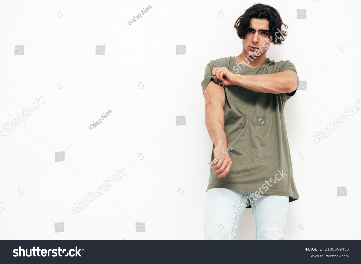 Portrait of handsome confident  stylish hipster lambersexual model.Sexy man dressed in over size T-shirt and jeans. Fashion male isolated in studio. Posing near white wall #2188599455
