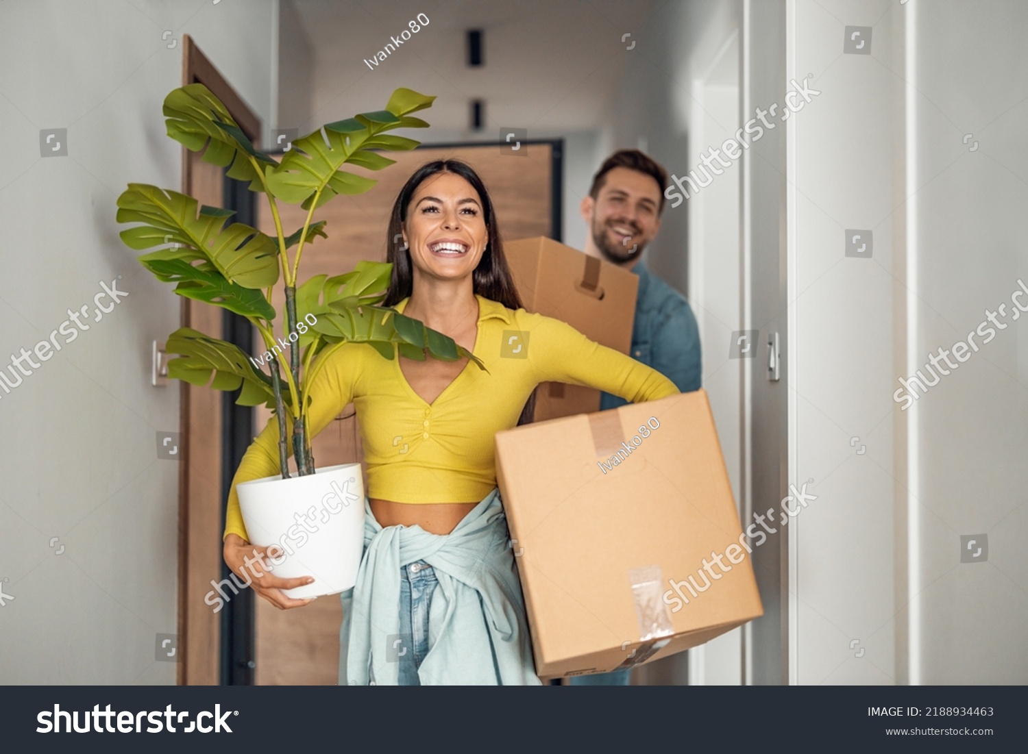 Young couple moving in new home.Couple is having fun with cardboard boxes in new house at moving day. #2188934463