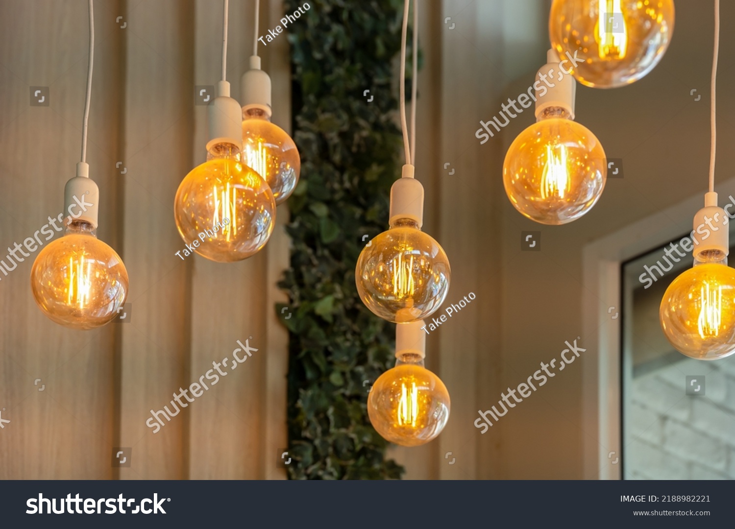 Vintage tungsten filament multiple lamps hanging from the ceiling on a white wires as an interior design concept. Energy and design concept #2188982221