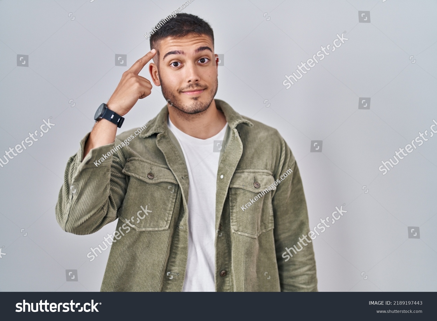 Young hispanic man standing over isolated background smiling pointing to head with one finger, great idea or thought, good memory  #2189197443