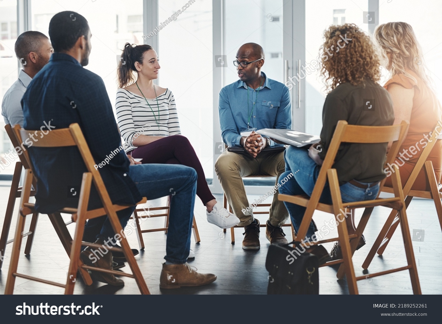 A group therapy session with diverse people sharing their sad problems and stories. People sitting in a circle talking about their mental health issues and looking for support, help and counseling #2189252261