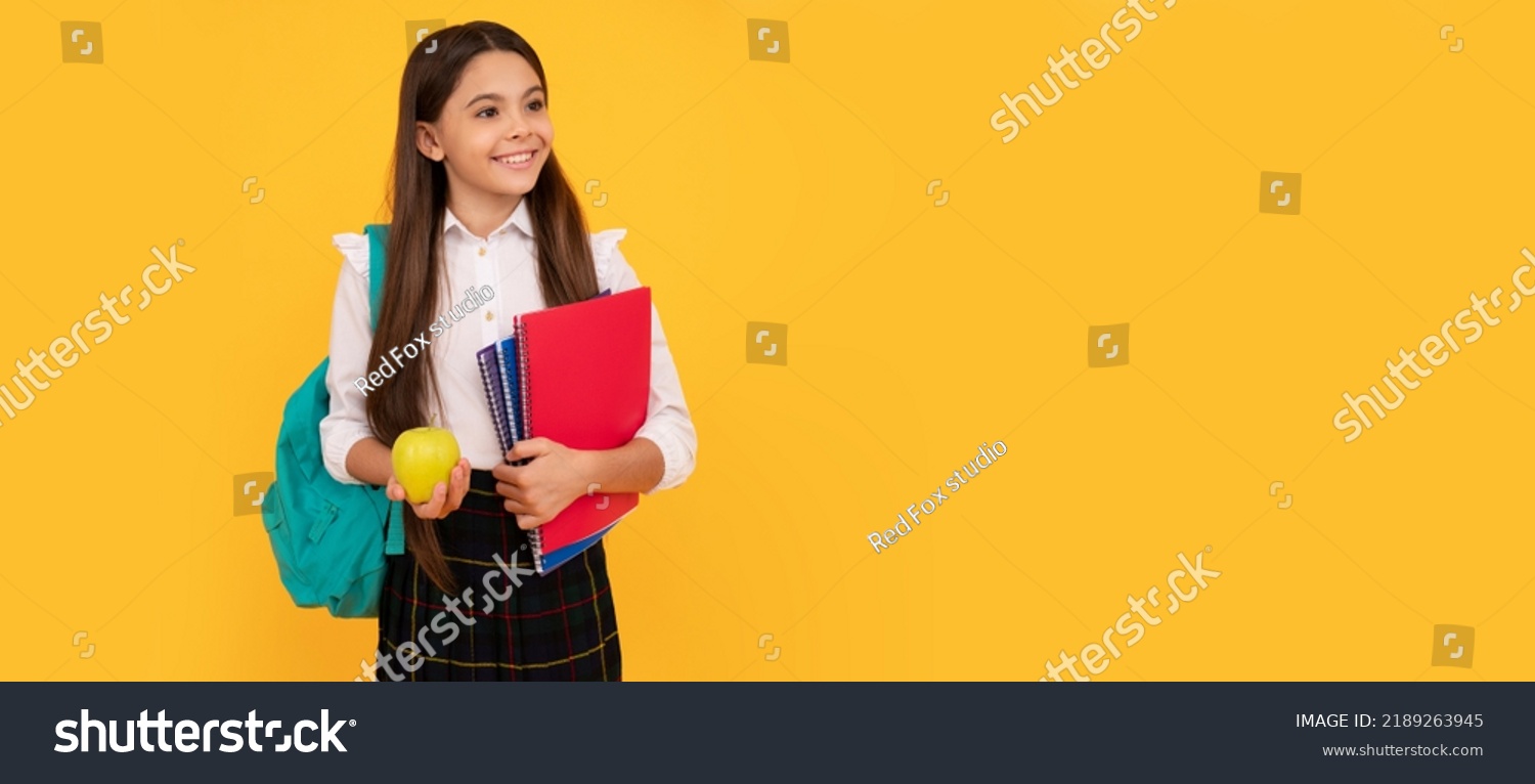 happy child with backpack and workbooks hold apple lunch in school uniform. Banner of school girl student. Schoolgirl pupil portrait with copy space. #2189263945