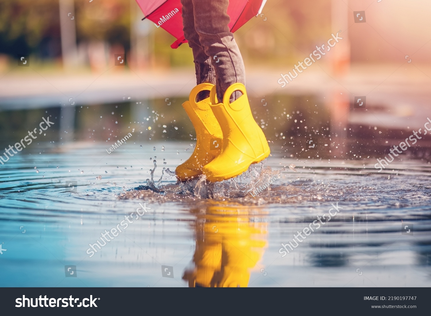 Child jumping in the puddle in yellow rubber boots #2190197747
