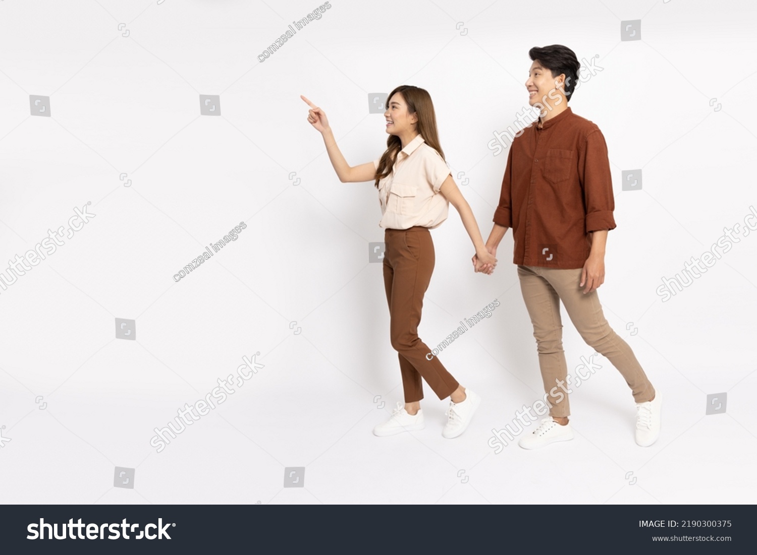 Young Asian couple walking and pointing to empty copy space isolated on white background, Full body composition #2190300375