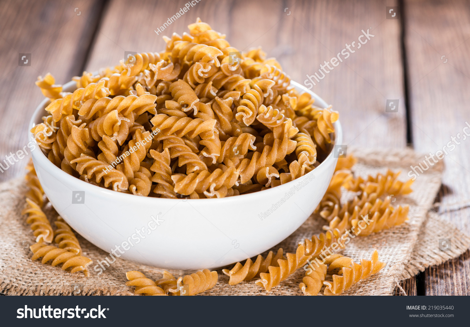 Portion of uncooked Wholemeal Fussili on wooden background #219035440