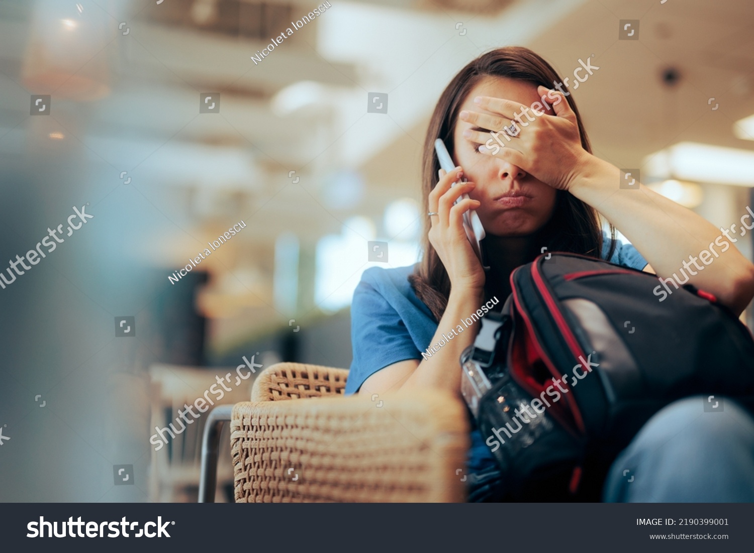 Unhappy Woman Talking on the Phone Waiting in an Airport 
Stressed traveler speaking on her cellphone feeling overwhelmed #2190399001