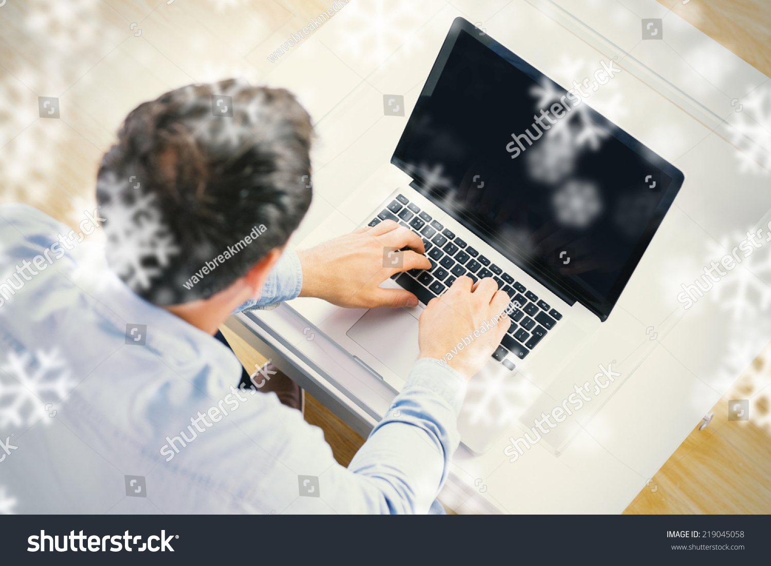 High angle view of casual man using laptop against snowflakes #219045058