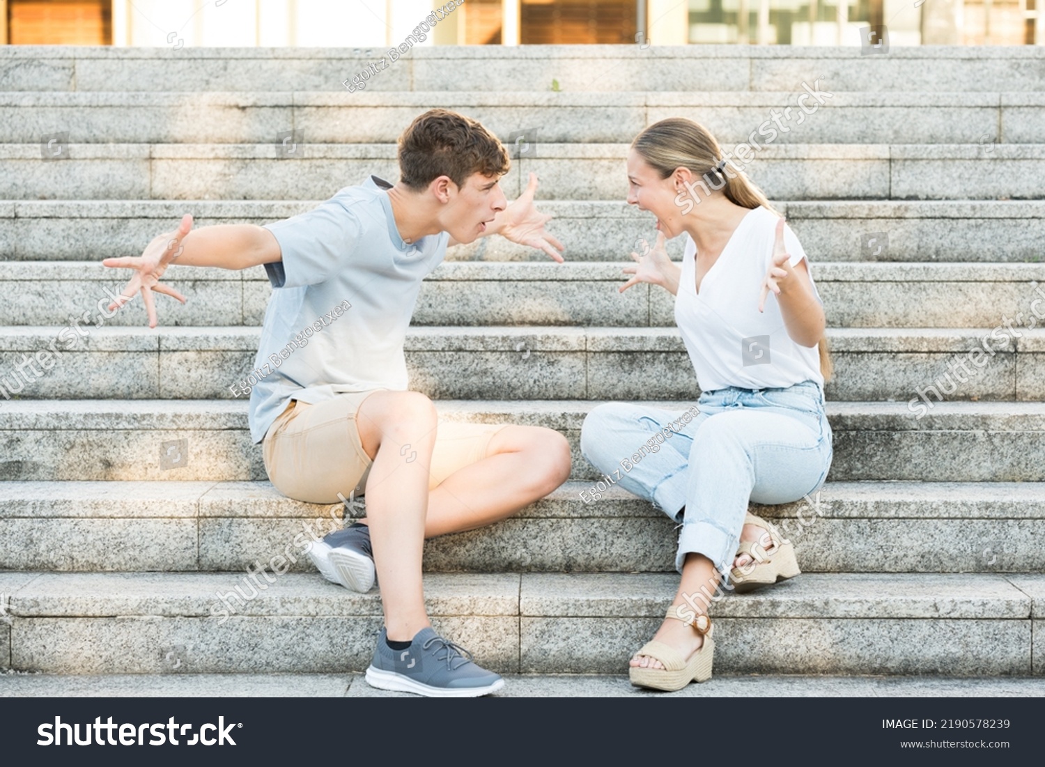 Teenager couple discussion. Toxic relationship concept. Boy and girl shouting sitting on stairs. #2190578239