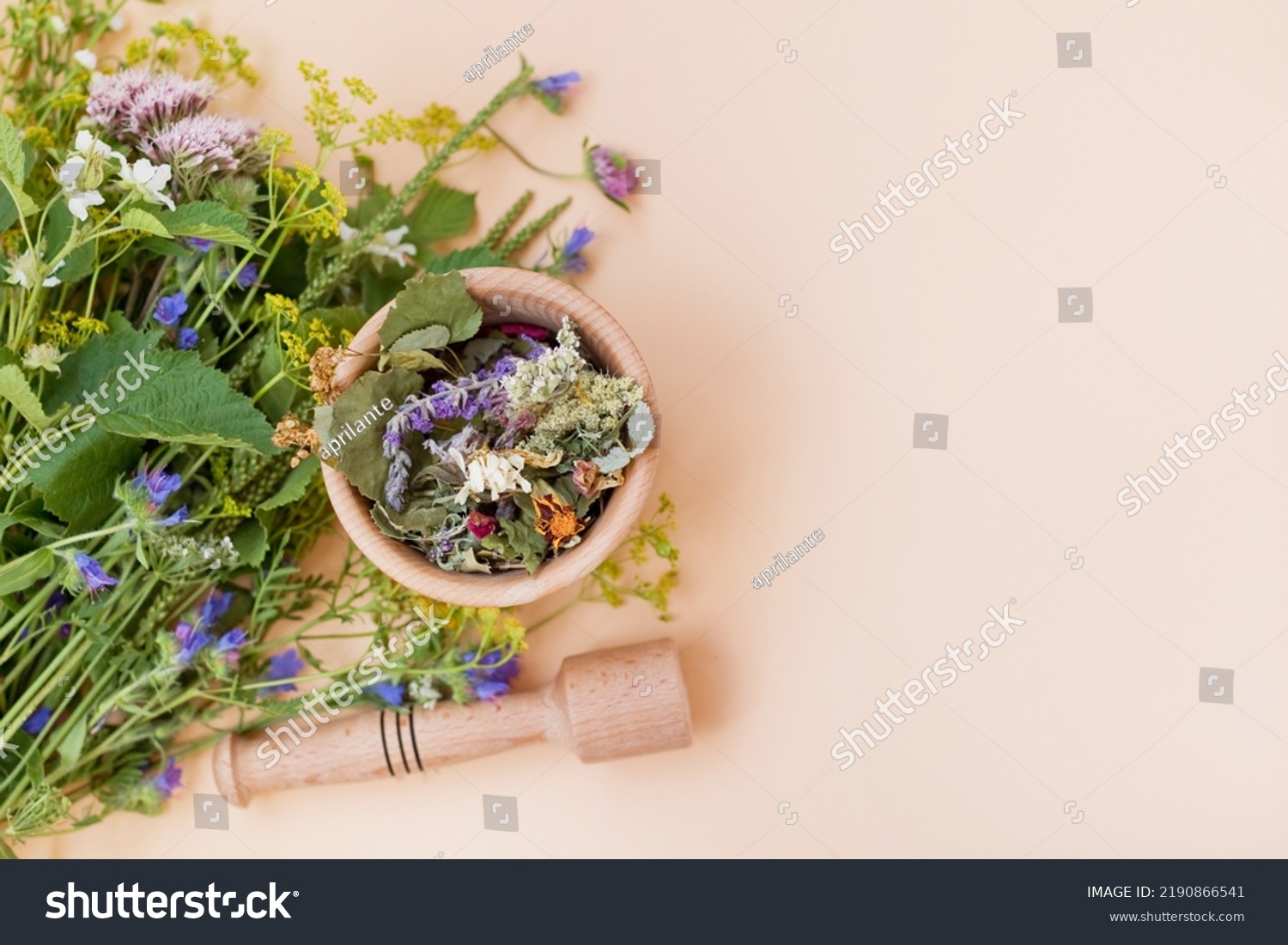 Homeopathy and herbal medicine concept. Bouquet of wildflowers and wooden mortar and pestle with dry herbs on a beige background with copy space #2190866541