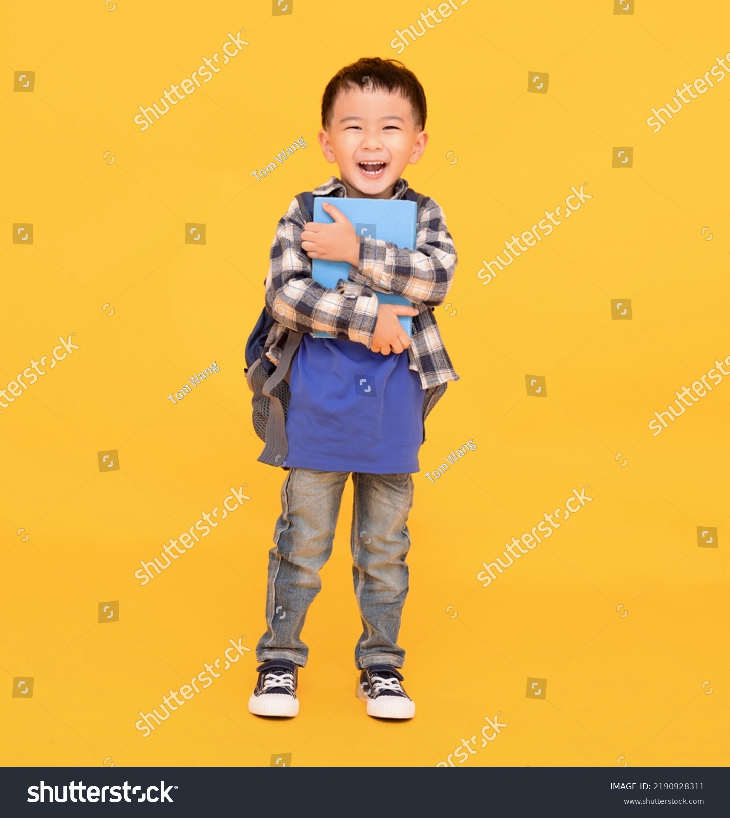 happy asian kid holding or hugging  big book over yellow background #2190928311