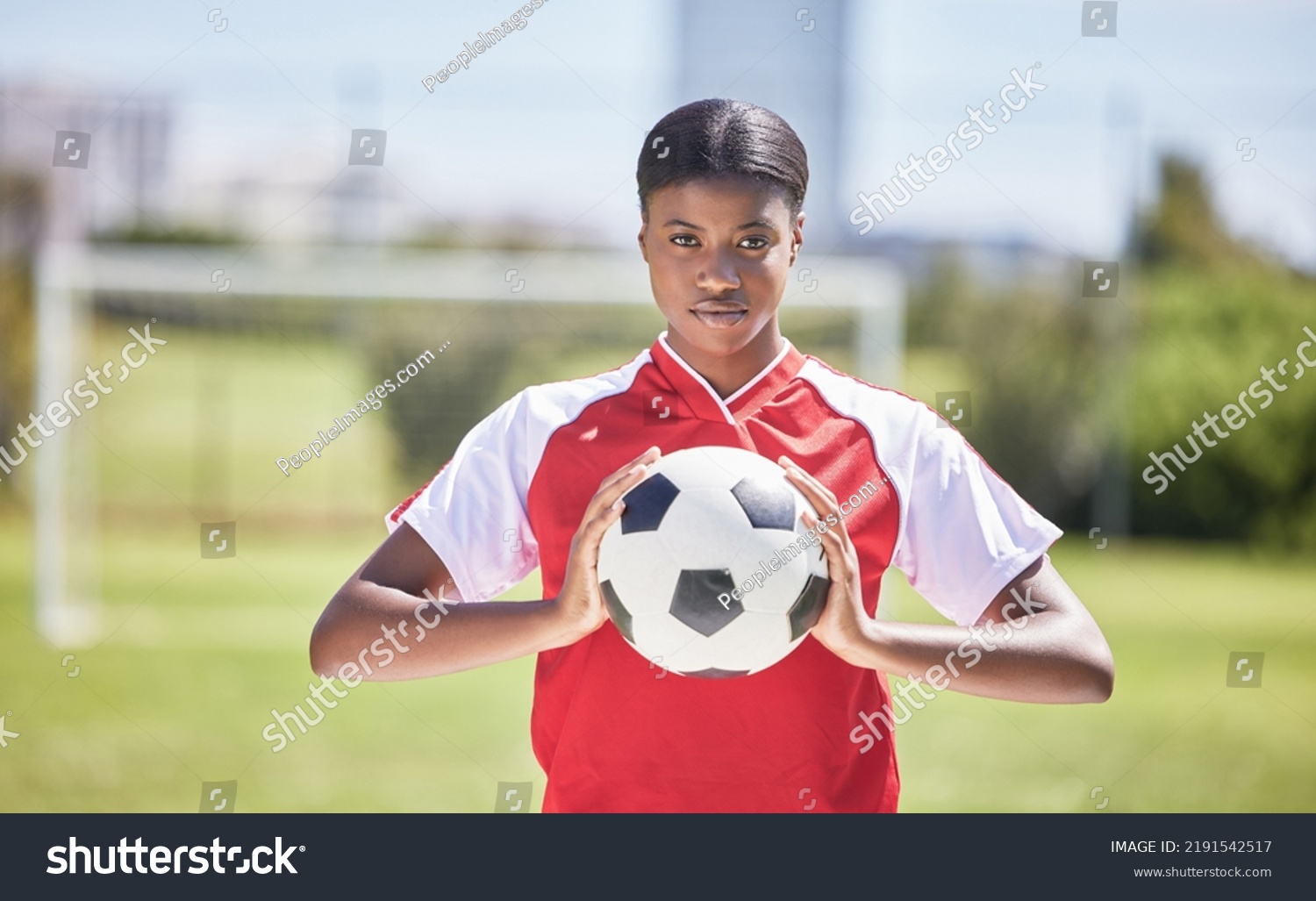 Soccer, football and sports with player, woman and athlete ready for a match, game or competition with ball on a pitch, field or stadium outdoor. Portrait of serious black female ready for training #2191542517