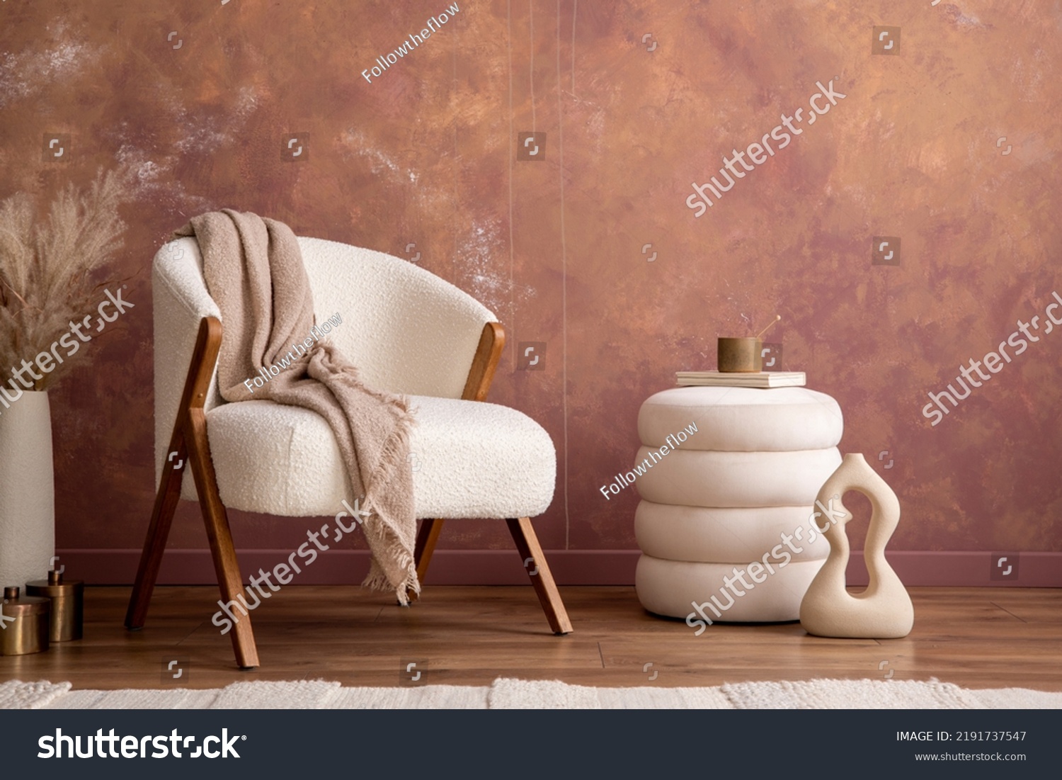 Interior design of aesthetic and elegant room with white boucle armchair, modern pouf, vase with dried flowers and personal accessories. Stylish home decor. Template. Copy space. Grunge wall.  #2191737547