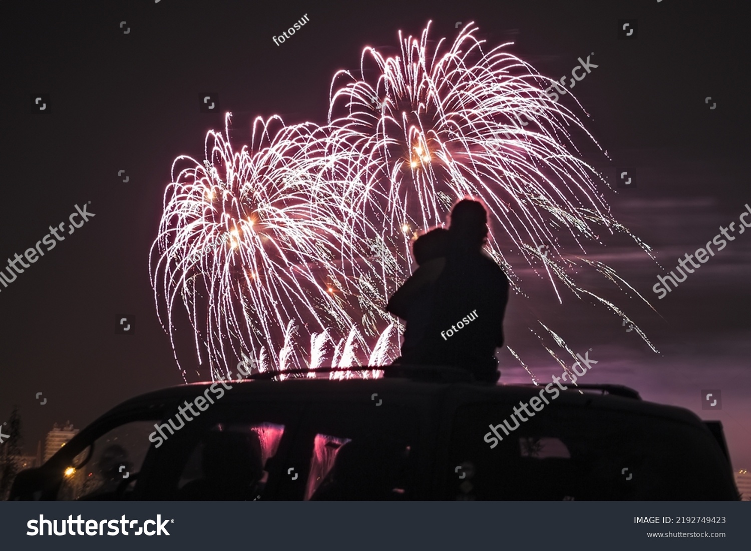 silhouette of a mother with her little daughter watching fireworks on the roof of their car #2192749423