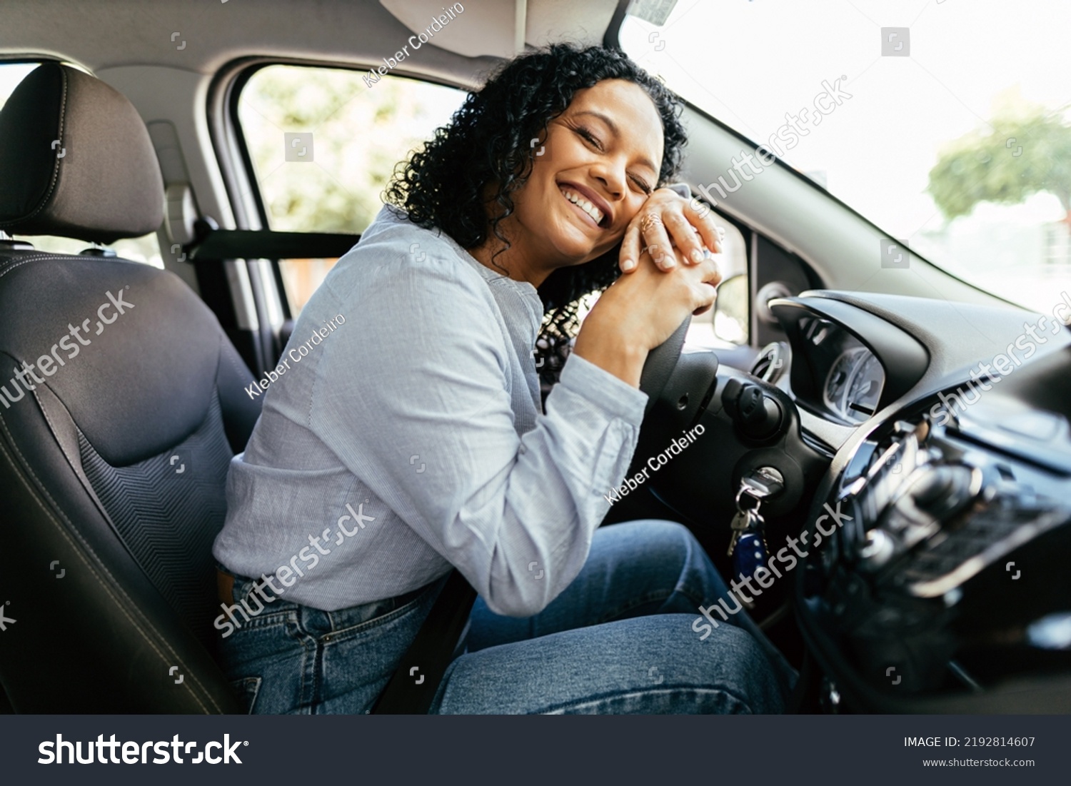 Young and cheerful woman enjoying new car hugging steering wheel sitting inside. Woman driving a new car. #2192814607