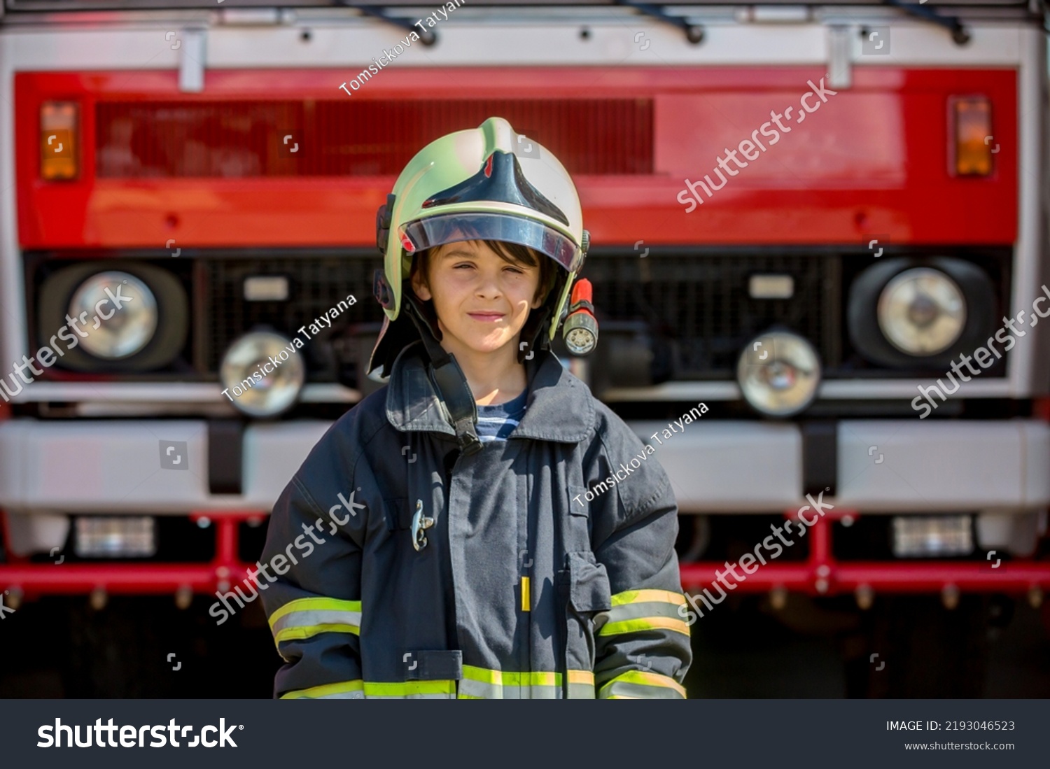 Child, cute boy, dressed in fire fighers cloths in a fire station with fire truck, childs dream #2193046523