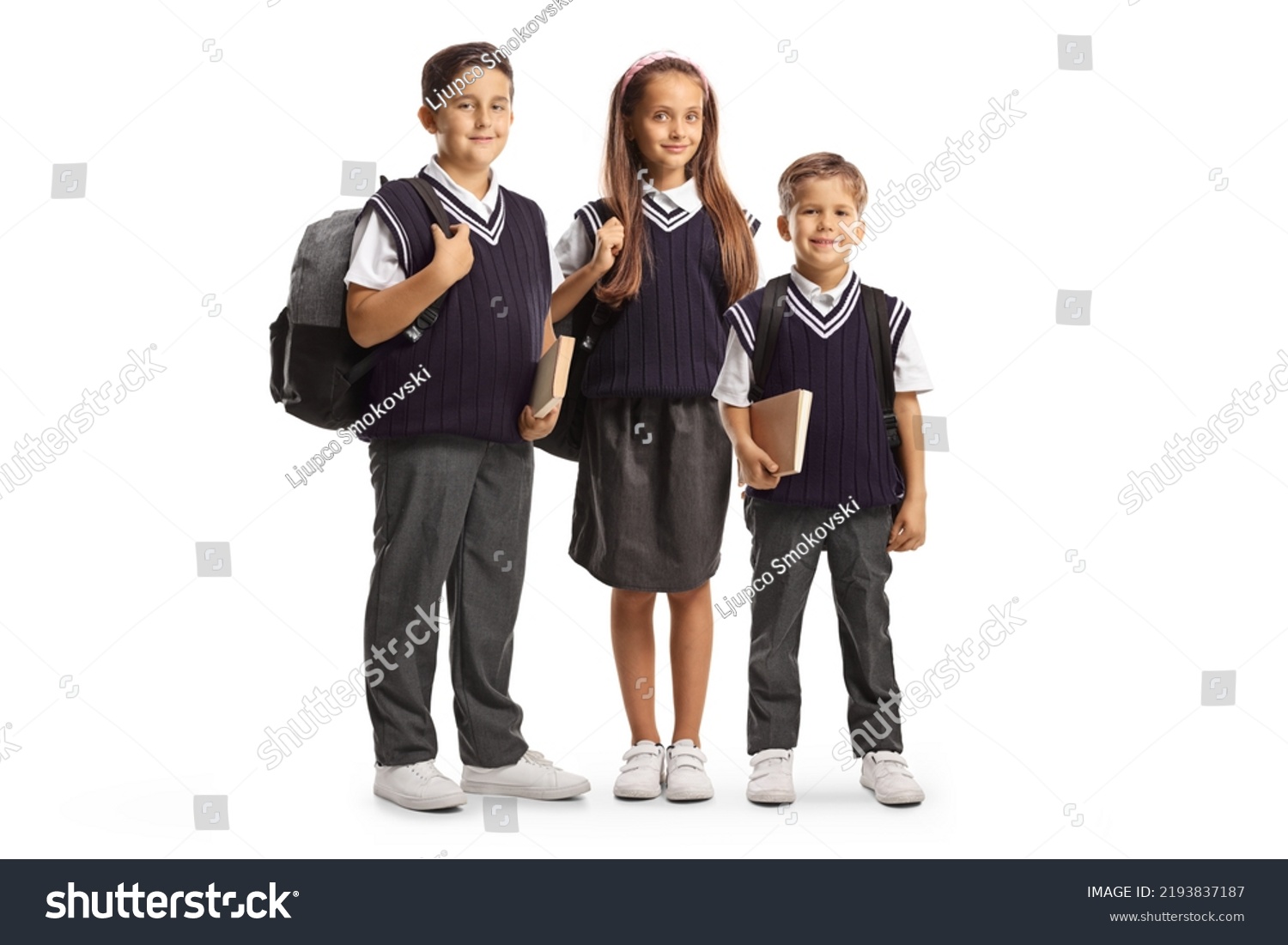 Two boys and one girl in school uniforms carrying backpacks isolated on white background #2193837187
