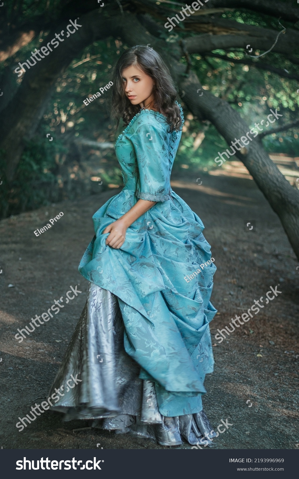 A young woman in a 19th century dress runs away along a forest path, a mystical atmosphere. Historical costume. Woman in a park or forest. #2193996969